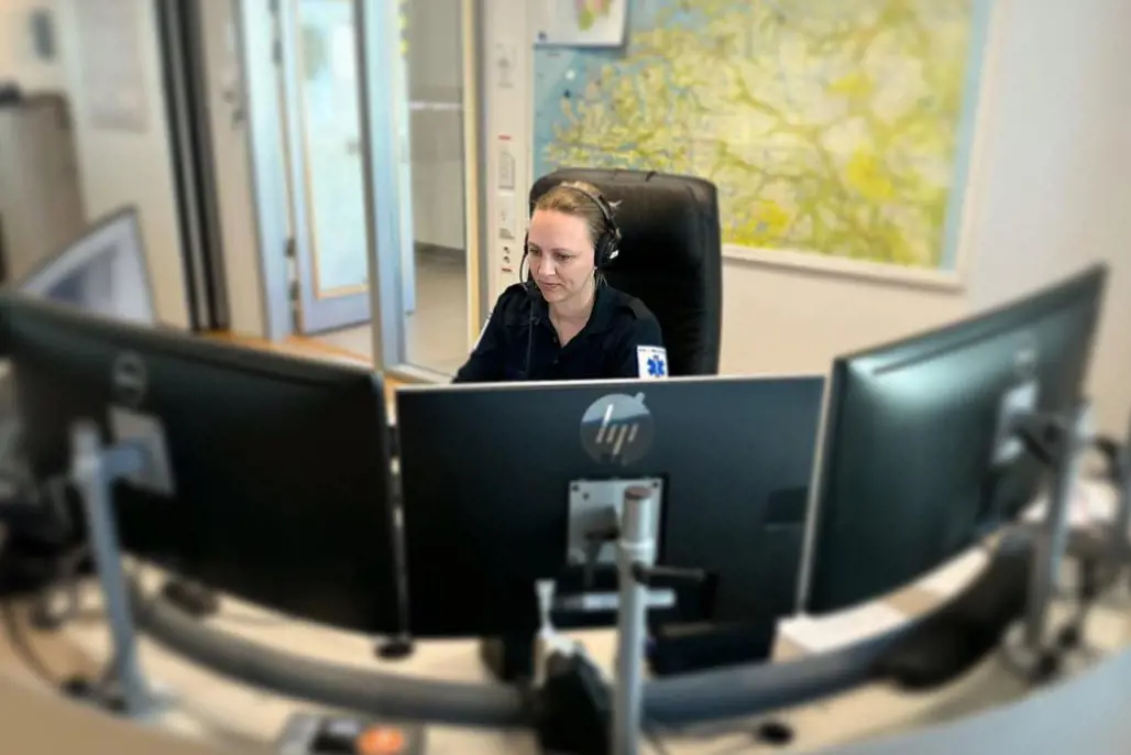 En person som sitter ved et skrivebord med en datamaskin og hodetelefoner på