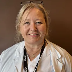 En dame med hvit skjorte og briller på hodet