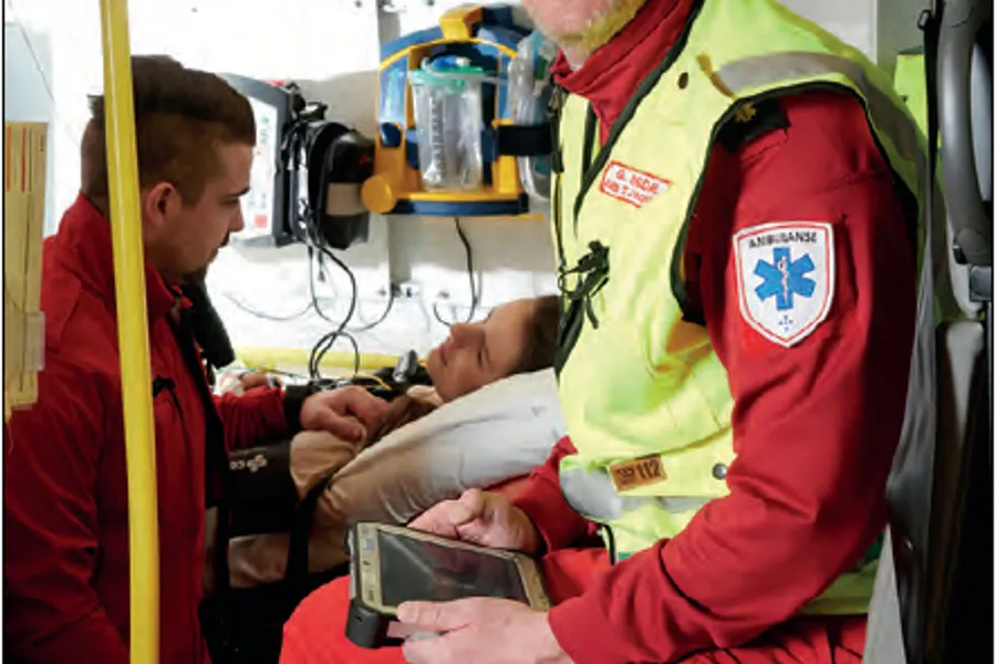 En person i en sikkerhetsvest som holder en baby i en sykehusseng