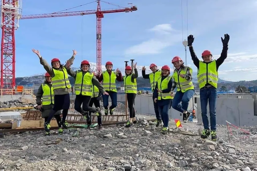 En gruppe mennesker i sikkerhetsvester som står på en byggeplass