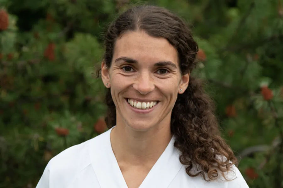 En person som smiler foran et tre