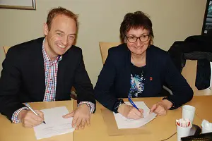 En mann og en kvinne som sitter ved et bord og skriver på papir