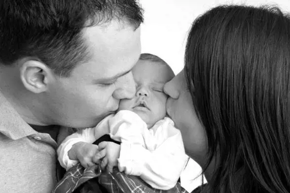 En mann og kvinne som kysser en baby