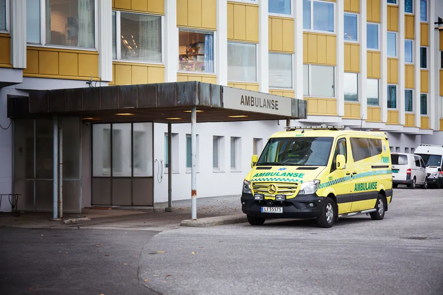 En gul ambulanse parkert foran et sjukehus
