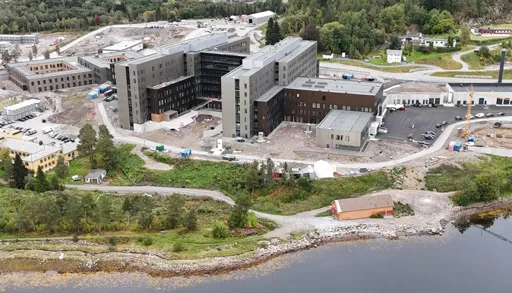 Dronebilde av Sjukehuset Nordmøre og Romsdal, Hjelset. Eit sjukehus ved fjorden. Arbeid med uteområdet gjenstår.